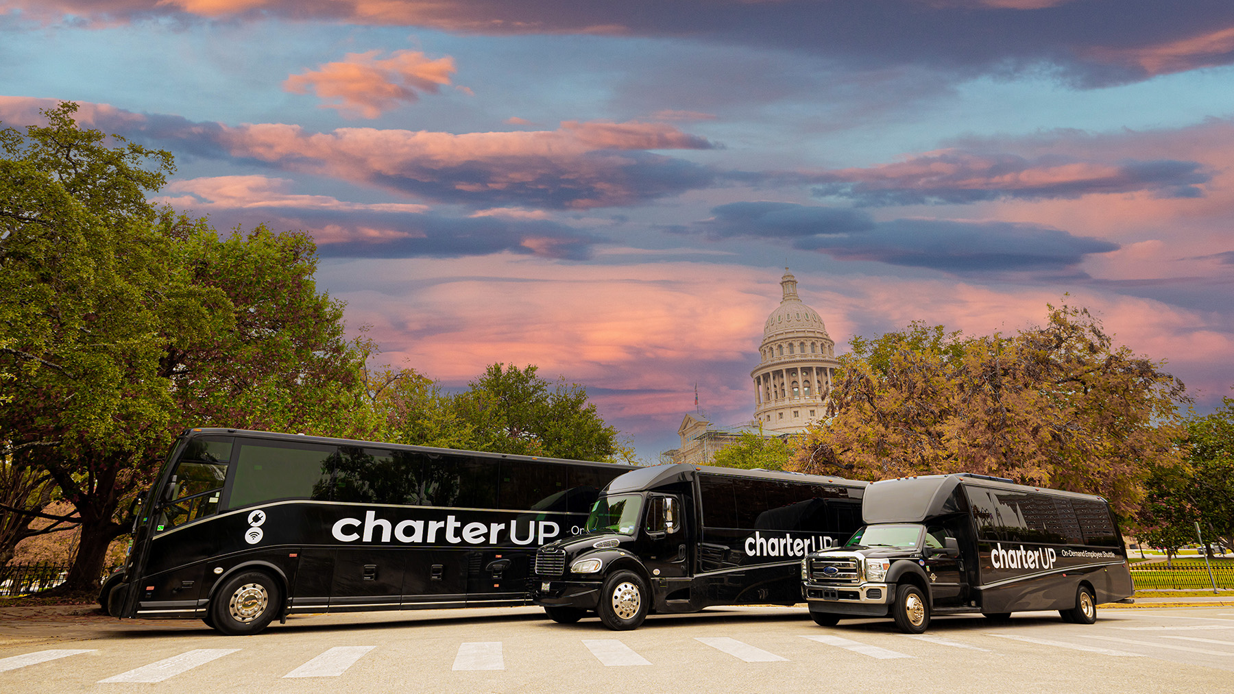 three charterup buses parked in a lot in front of the texas state capitol