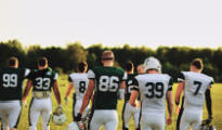 A football team walking on the field facing away from camera