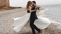 Bride and groom embrace on a beach