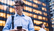 New York City businessperson smiles while sending a text message.