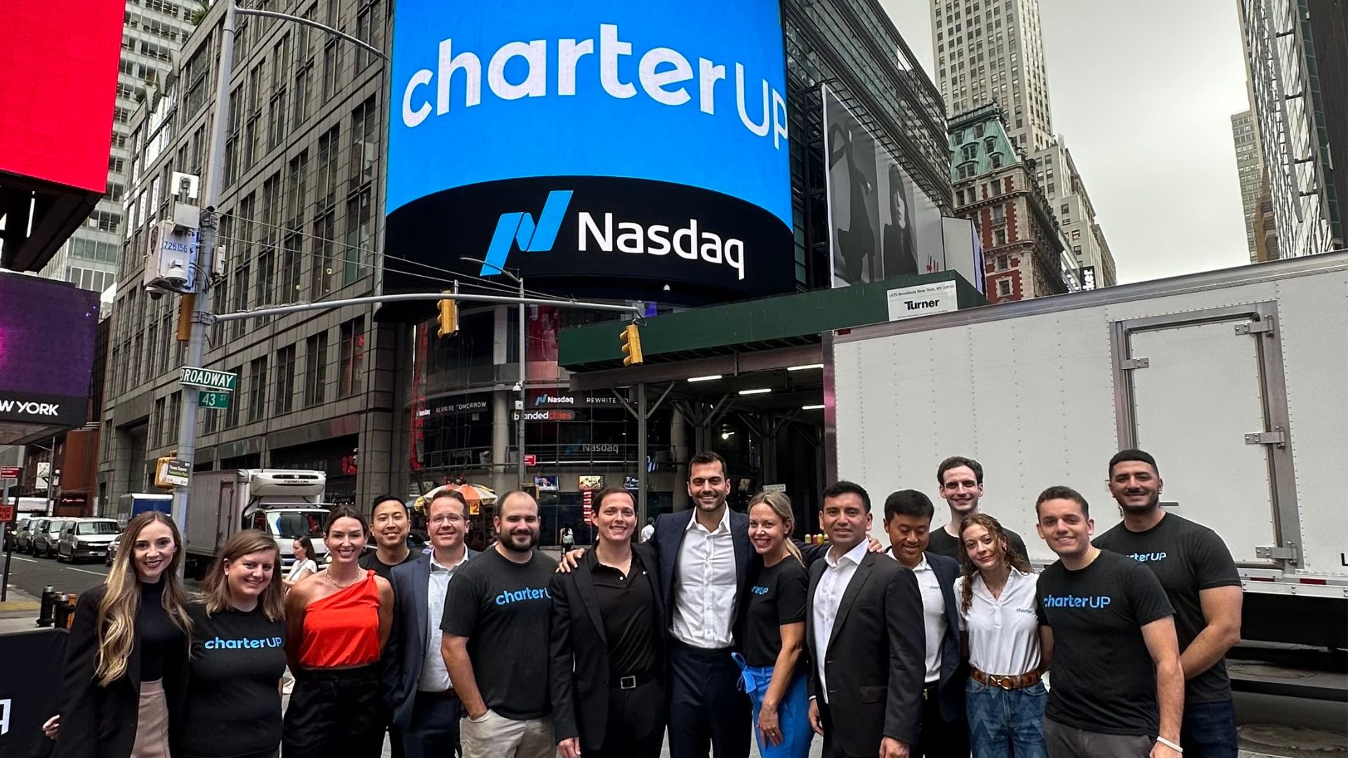 The CharterUP team poses in front of the Nasdaq MarketSite in celebration of the company's 111,130% growth.