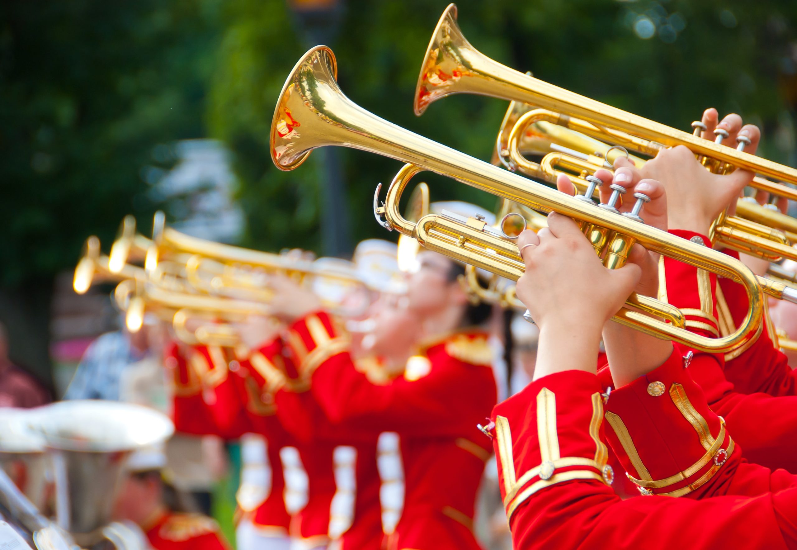 A photo taken from the side of a marching band wearing red uniforms with gold instruments.