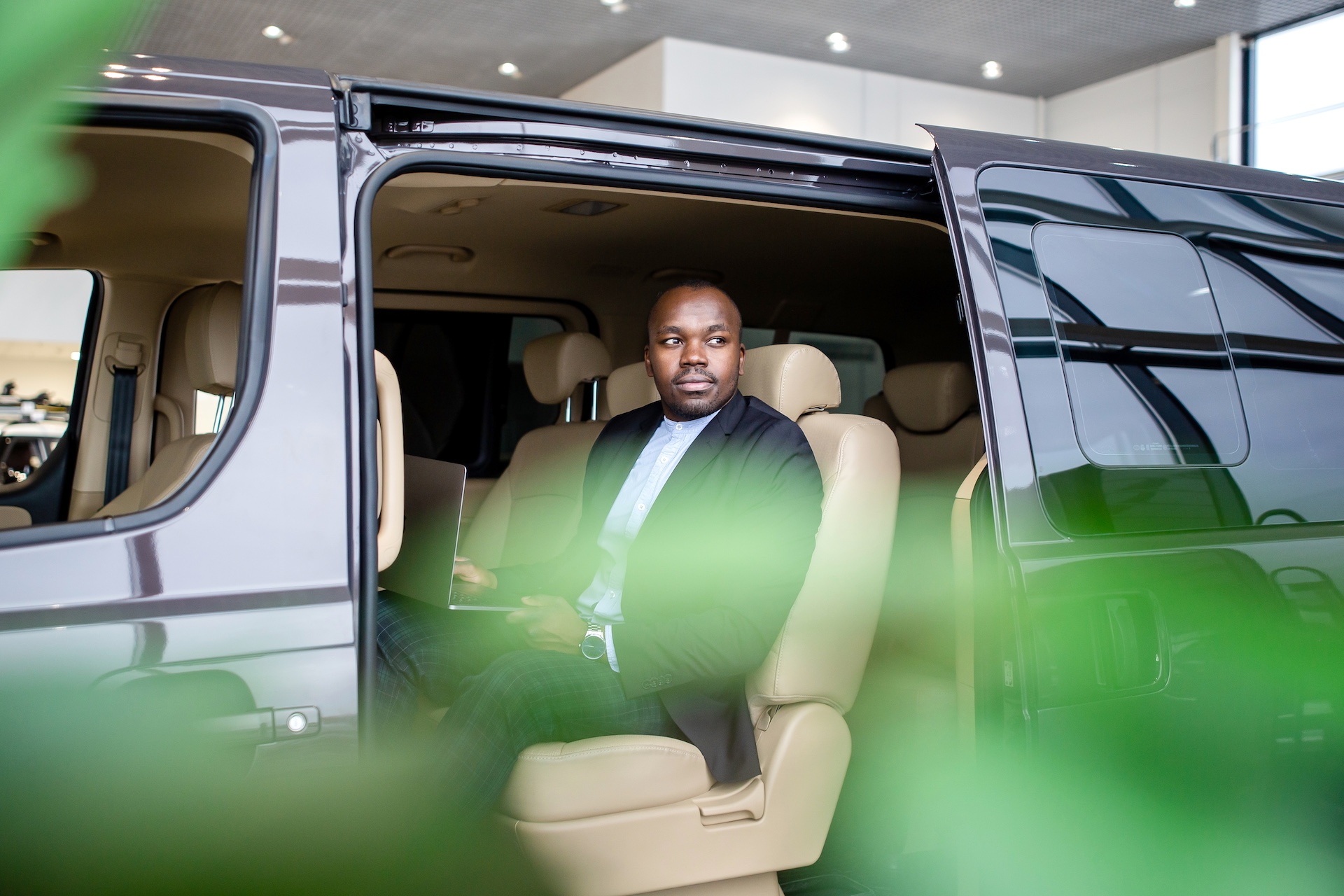 Black male businessman sitting in the passenger seat of a car in a luxury sprinter van.