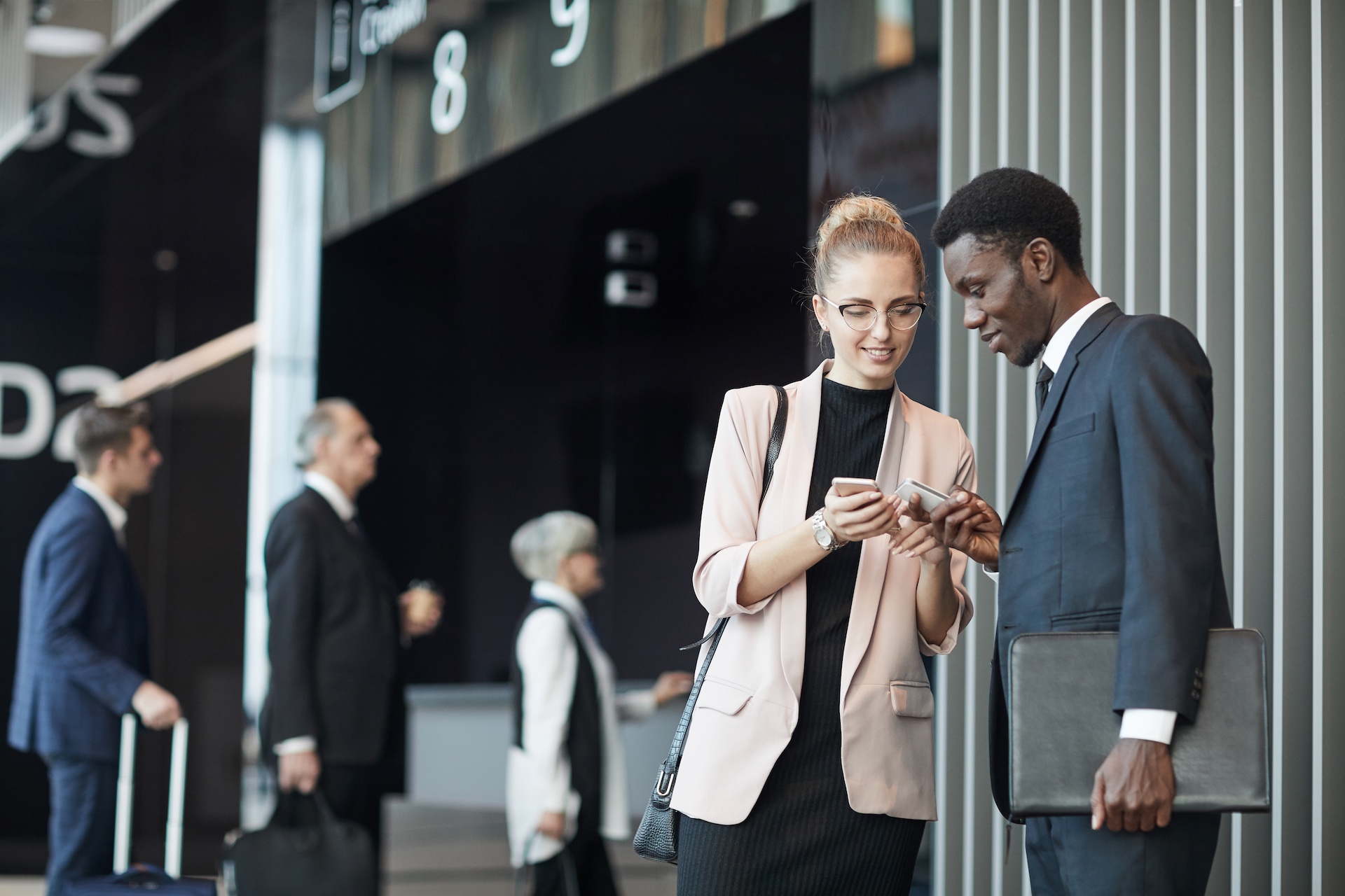 Young business partners standing and exchanging their phone numbers before the flight at the airport