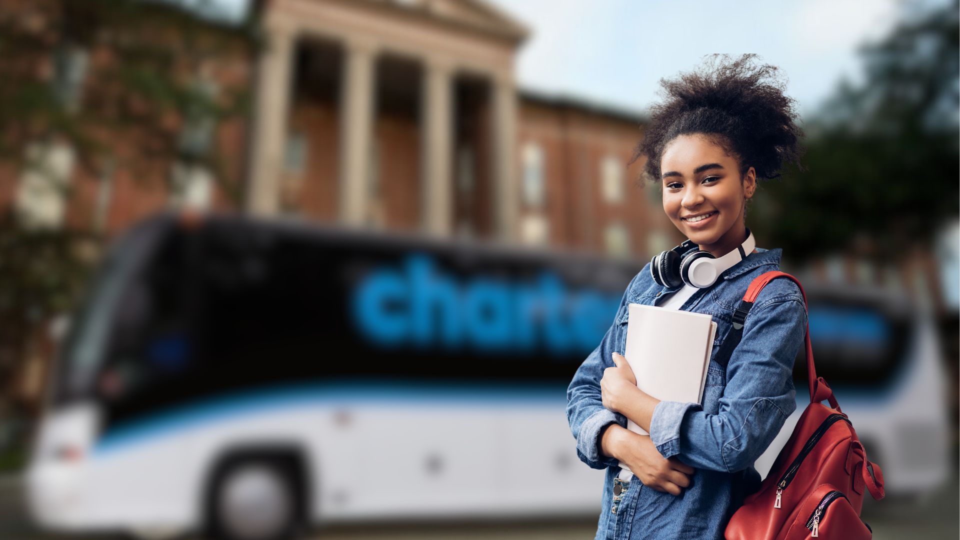 A university student stands in front of a CharterUP campus shuttle.