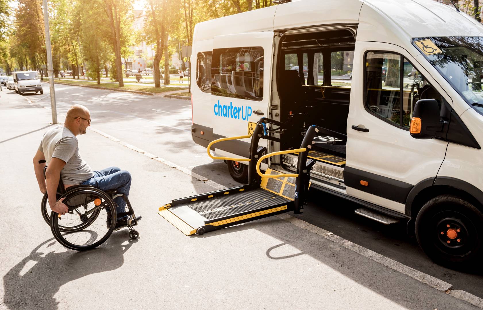 A man in a wheelchair moves to the lift of a specialized CharterUP healthcare shuttle